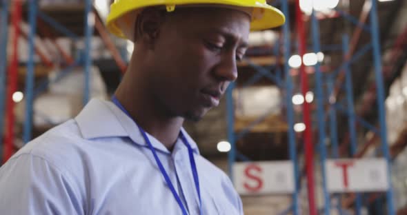 Portrait of a young man wearing a hard hat in a warehouse 4k