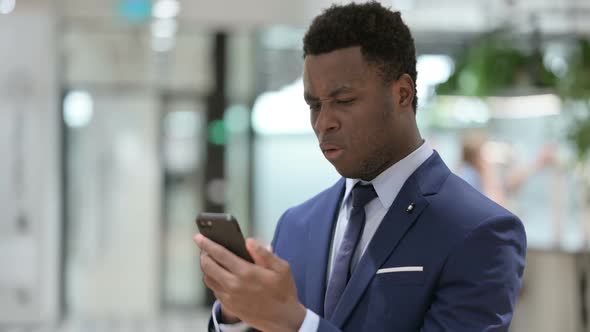 Upset African Businessman Reacting to Loss on Smartphone