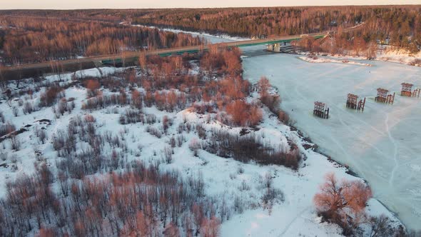 Beautiful Winter Landscape with Frozen River and Bridge at Sunset Aerial View