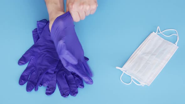 Doctor putting on gloves and taking respiratory mask