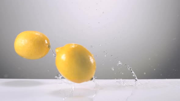 Slo-motion whole lemons falling on water