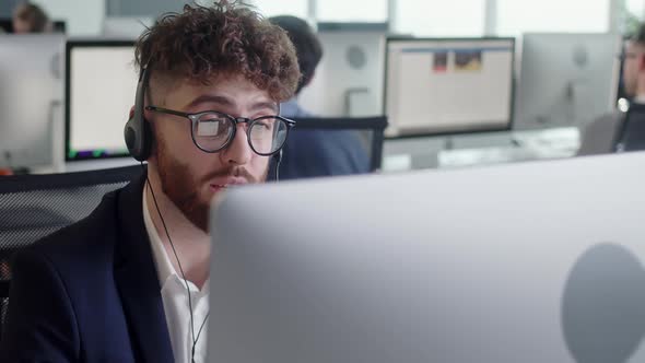 Close Up Portrait of a Technical Customer Support Specialist Talking on a Headset While Working on a