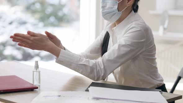 Unrecognizable Caucasian Young Woman in Covid19 Face Mask Disinfecting Hands with Sanitizer at