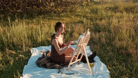 Happy girl painting outdoors at sunset