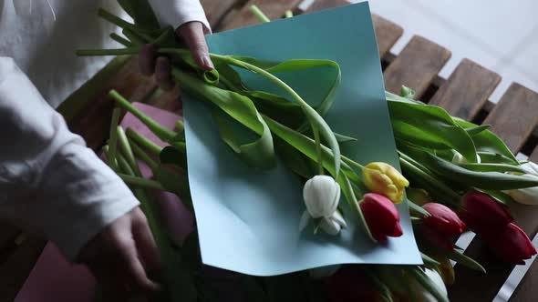 Woman wrapping tulips in paper for sale