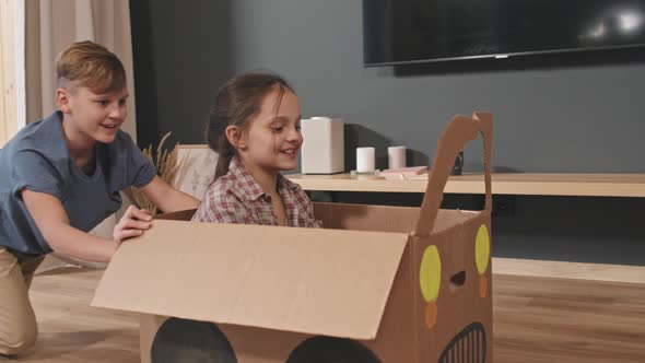 Cute Siblings Playing With Cardboard Car