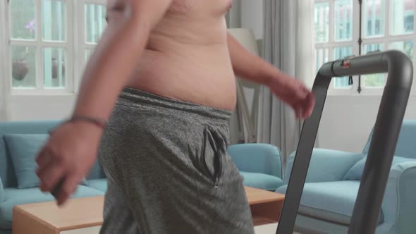Asian Fat Man Wearing No T-Shirt And Training On Walking Treadmill At Home