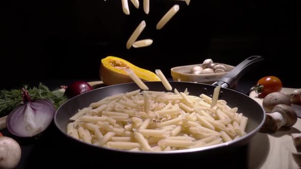 Frying Pan with Raw Pasta Macaroni. Fall in Slow Motion