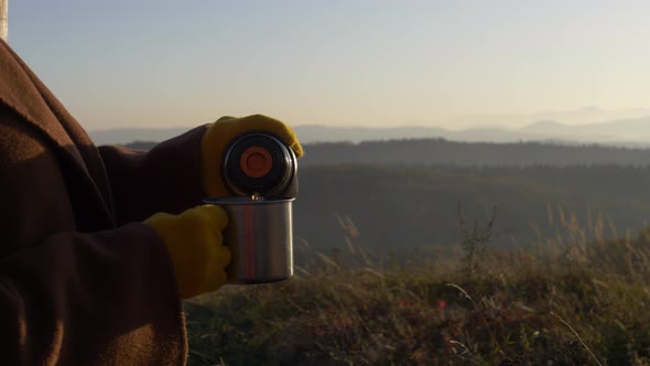 woman hold mug of tea in mountains Sudetes in November in sunset