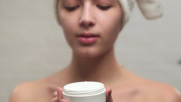 Woman in Towel Putting Cream on Face