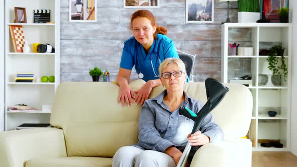 Pretty Nurse in Nursing Home and Old Woman Sitting on Couch