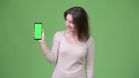 Young Happy Beautiful Woman Showing Phone Against Green Background