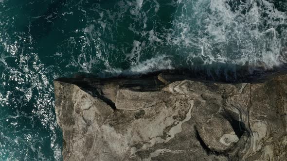 Aerial Overhead Top Down Birds Eye View of Big Ocean Waves Crashing on Rocks