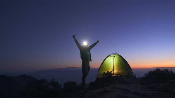 Joyful Tourist Set Up a Tent on a Mountain Top at Dusk After Sunset and Preparing To Spend the Night