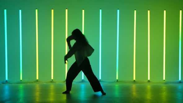 Young Woman Dancer Dancing Contemporary in the Studio Against the Background of Multicolored Neon