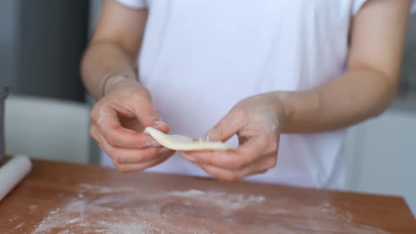 A Woman Uses a Spoon to Put the Filling on the Dough