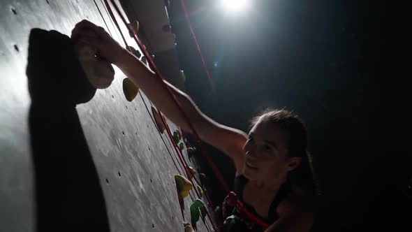 Female Climber Training on a Climbing Wall Practicing Rockclimbing and Moving Up Endurance Training