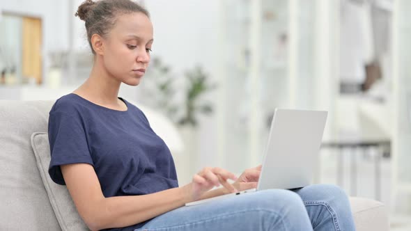 Excited African Woman Celebrating Success on Laptop at Home 