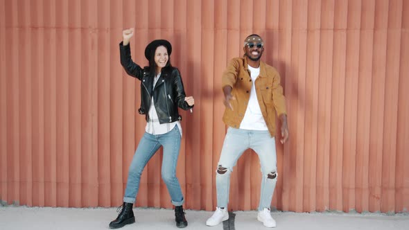 Cheerful Couple AfroAmerican Man and Mixed Race Woman Dancing Having Fun on Wall Background