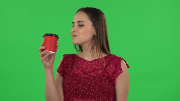 Portrait of Tender Girl in Red Dress Is Enjoying Coffee. Green Screen