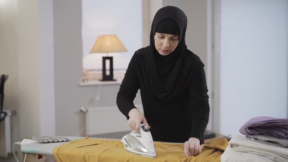 Portrait of Tired Muslim Woman in Black Traditional Clothes Doing Housework. Young Beautiful Lady