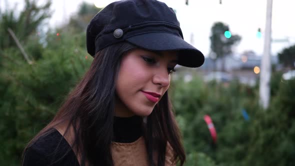 A young woman shopping on a Christmas tree lot with green douglas fir conifers in a holiday botanica