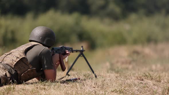 Armed Man Unloading Machine Gun with Machine Gun in His Hands Soldier Lying with Gun Military Army