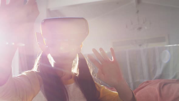 Happy asian girl at home, sitting on floor in living room enjoying using vr headset, backlit