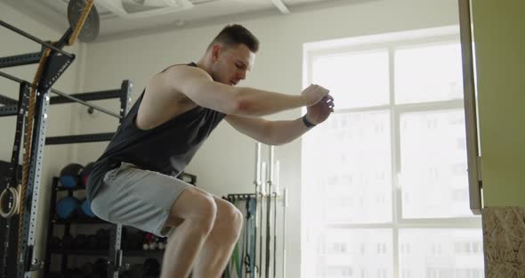 Young Muscular Athlete Works Out in a Modern Gym Making Box Jumps Exercise