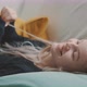Young blonde woman laying on couch playing with her hair while smiling - VideoHive Item for Sale