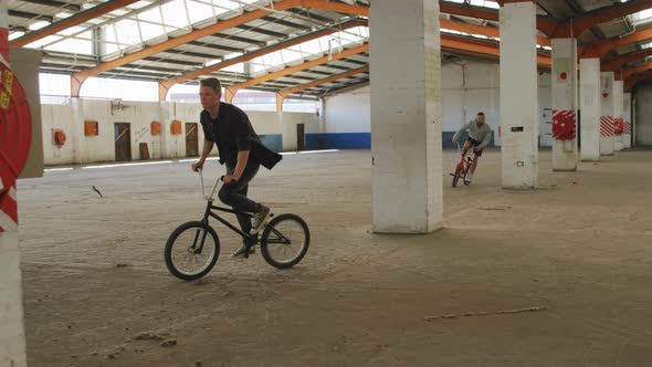 BMX riders in an empty warehouse