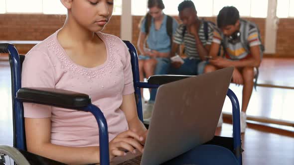 Disabled schoolgirl using digital tablet with classmates in background