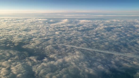 Incredible view from the cockpit of an airplane flying high above the clouds leaving a long white co