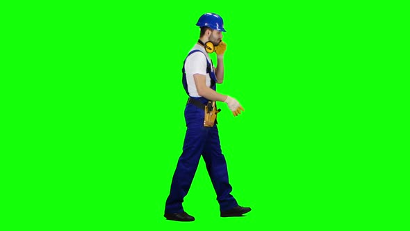 Foreman in a Helmet and Gloves Speaks on the Phone. Green Screen. Side View