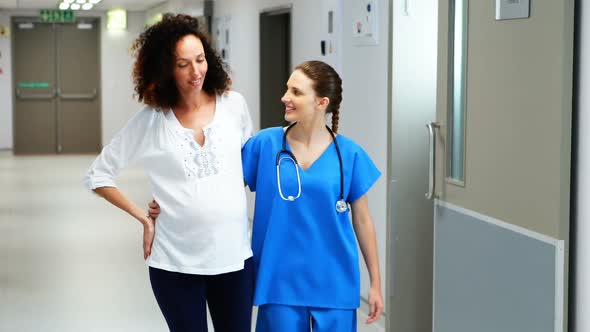 Doctor interacting with pregnant woman in corridor