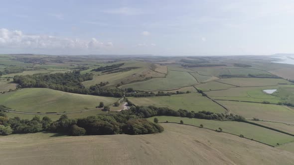Wide aerial shot tracking across the fields surrounded by Chesil Beach and the Village of Abbotsbury