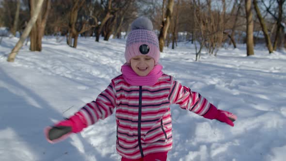 Child Girl Running on Snowy Road Fooling Around Smiling Looking at Camera in Winter Park Forest