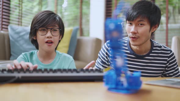 asian boy child with father control robot arm on Digital tablet and computer