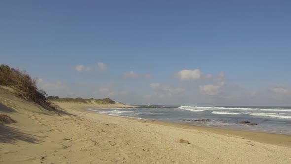 Sand dunes, beach vegetation, waves and a beautiful blue sky.