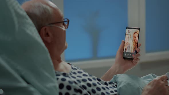 Sick Elder Patient Talking on Videocall with Family in Hospital Ward