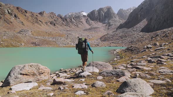 Hiker Tourist with Backpack Walking Near Mountain Lake