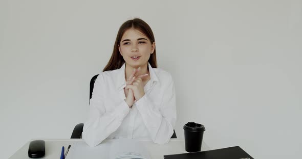 Happy Girl Talking with Gestures at Camera When Sitting at Workplace in Office