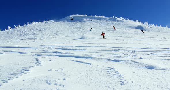 People snowboarding on snowy mountain