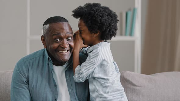 Little Cute Daughter Whispering in Dad's Ear Telling Secret Mystery Says Funny Joke Loving Father