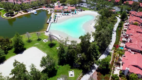 Aerial fly over of a lake club sand lagoon pool at a community lake center angle 1