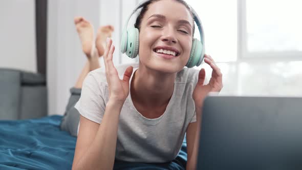 A happy woman wearing headphones while using laptop