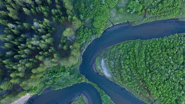 Top down view of river winding through green meadow