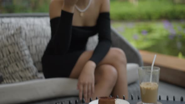 An Asian Girl Sitting on the Couch and Eating Slice of Cake at Restaurant