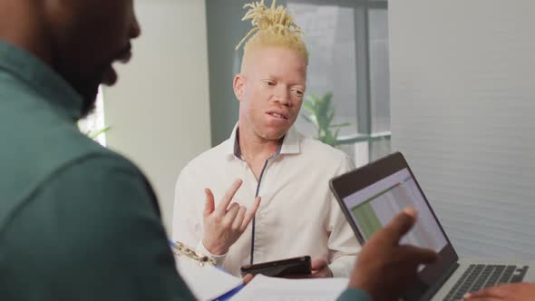 Diverse business people discussing with laptop and documents in creative office