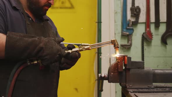 Caucasian male factory worker at a factory standing in a workbench and welding